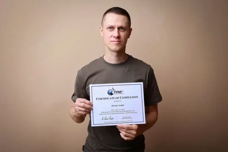 TRE- Muž drží v ruce certifikát TRE